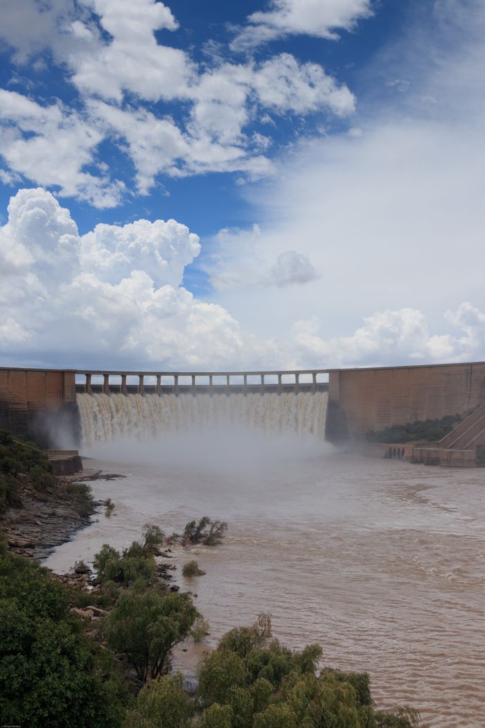 Majestic dam with water flowing under a cloudy sky, showcasing engineering and nature's force.